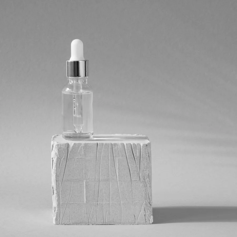 A glass dropper serum bottle on a stone plinth, representing the skincare and beauty category