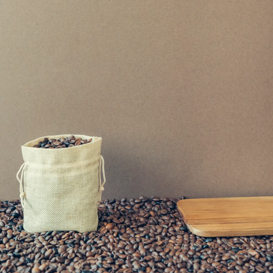 A drawstring sack of roasted coffee beans on a wooden board, representing the coffee and pantry category