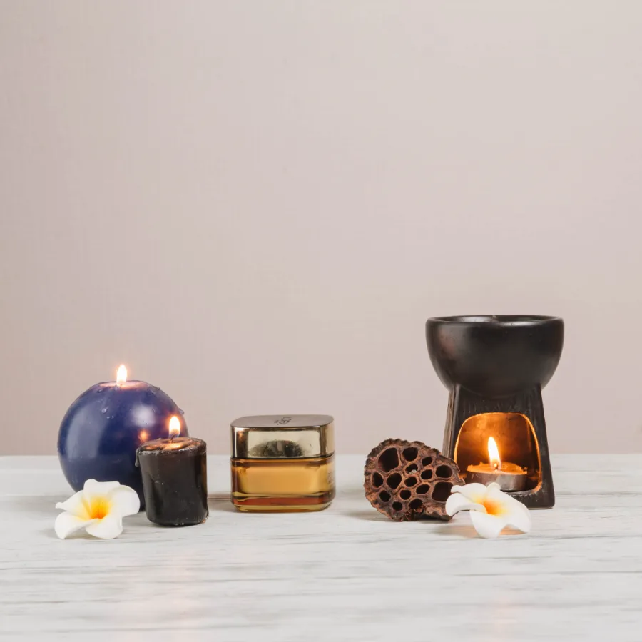 Lit candles beside spa stones and folded linen, representing the home and fragrance category